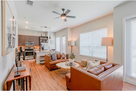 a living room and kitchen with a couch and a ceiling fan